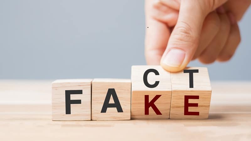 Business man hand holding wooden cube with flip over block FAKE Fake or Real Gambling Awards